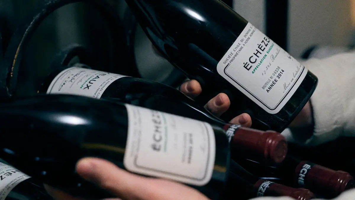 Person håller flera flaskor vin med etiketten ÉCHÉZEAUX